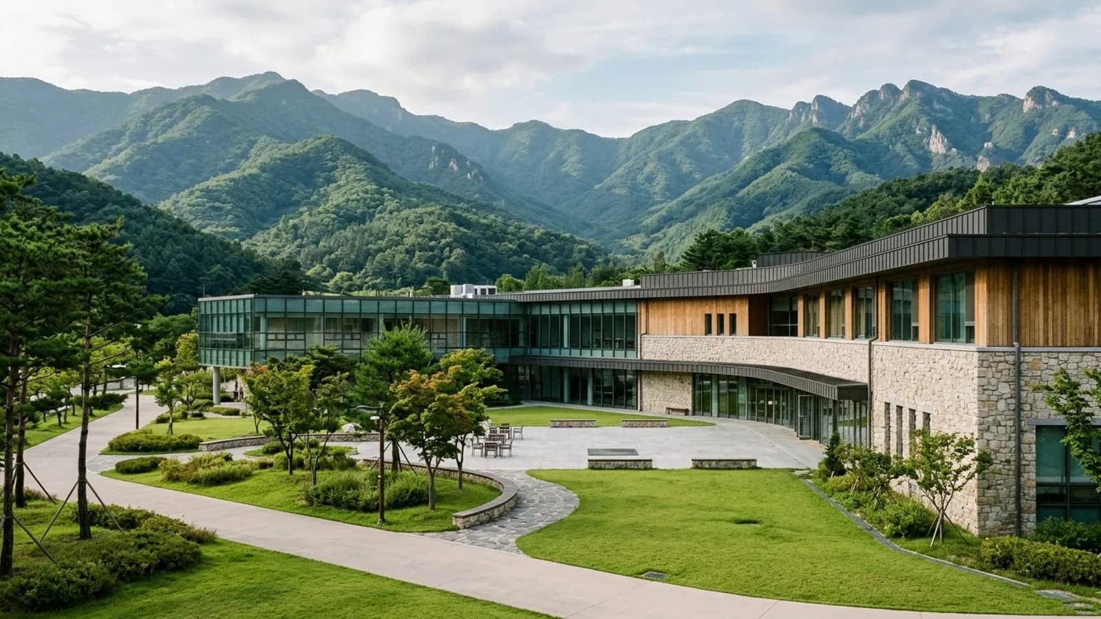 산세가 보이는 자연 풍경 속에 현대적인 교육 시설 건물이 자리 잡은 전경 모습.